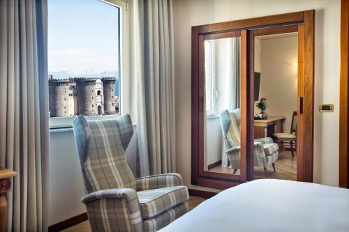 那不勒斯地中海那不勒斯万丽酒店的酒店的客房 - 带一张床、椅子和窗户