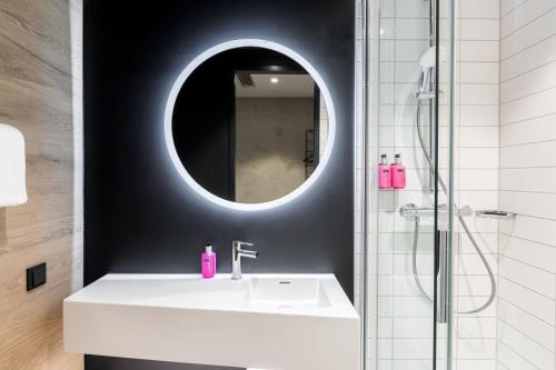 维尔茨堡Moxy Wuerzburg的浴室设有白色水槽和镜子