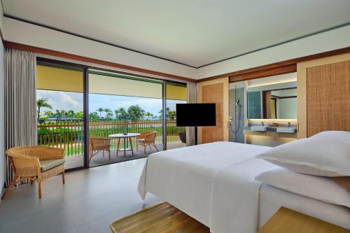 TanjungbingaSheraton Belitung Resort的一间带大床的卧室和一个阳台