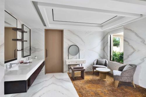 班加罗尔JW Marriott Hotel Bengaluru Prestige Golfshire Resort & Spa的一间带水槽、镜子和椅子的浴室