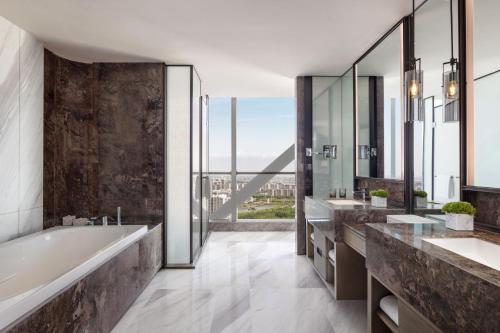 银川银川 JW 万豪酒店的一间带两个盥洗盆和浴缸的浴室以及大窗户。