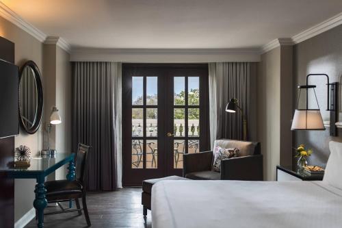查尔斯顿The Lindy Renaissance Charleston Hotel的配有一张床、一张书桌和一扇窗户的酒店客房