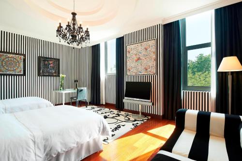 瓦伦西亚瓦伦西亚威斯丁酒店的一间卧室配有一张床、一台电视和吊灯。