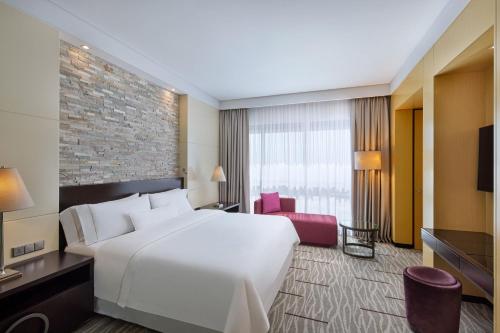 麦纳麦巴林威斯汀市中心酒店的酒店客房带白色的床和砖墙