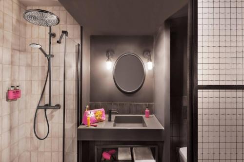 里尔Moxy Lille City的浴室配有盥洗盆和带镜子的淋浴