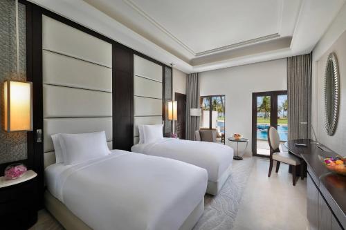 马斯喀特Al Bustan Palace, a Ritz-Carlton Hotel的酒店客房配有两张床和一张书桌