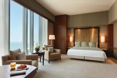 多哈JW Marriott Marquis City Center Doha的酒店客房带一张床、椅子和窗户