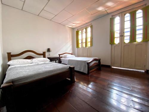 SalaminaHospedaje Casa Real的客房内设有两张床,铺有木地板,设有窗户。