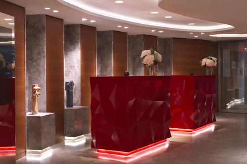 巴黎Renaissance Paris Republique Hotel & Spa的大堂的红色讲台上挂着鲜花