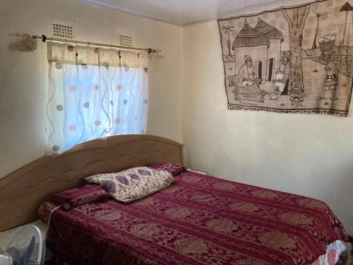 KazungulaNakawa Community Campsite的一间卧室配有一张带紫色毯子的床和窗户。