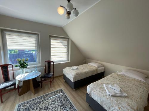DziemianyHotel Janta的一间卧室设有两张床、一张桌子和一个窗口