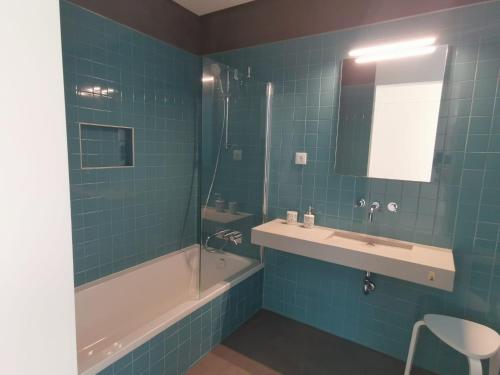 卡罗拉Galé T3的蓝色瓷砖浴室设有浴缸和水槽