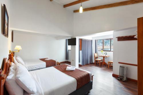 库斯科Hotel Amerinka的酒店客房配有两张床和一张书桌