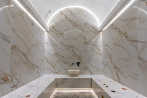 塔什干MODERNO Hotel的浴室设有白色大理石墙壁和水槽