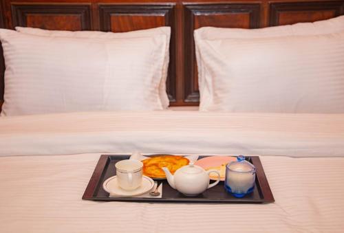 卡拉奇Hotel Inn Karachi的床上的食品和咖啡托盘