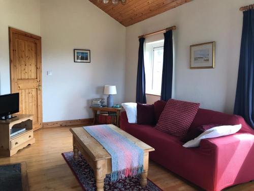 巴利康尼利Kilronan Cottage的客厅配有红色沙发和茶几