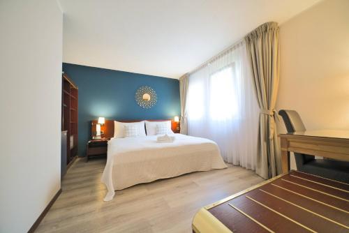 洛桑洛桑郁金香酒店的卧室配有白色的床和蓝色的墙壁