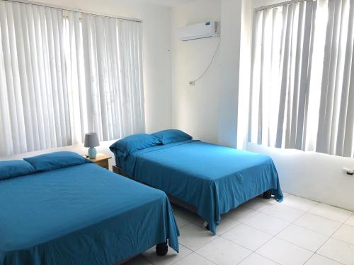 普拉亚斯Flor de Lis Beach House, villa vacacional的一间卧室设有两张蓝色的床和窗户