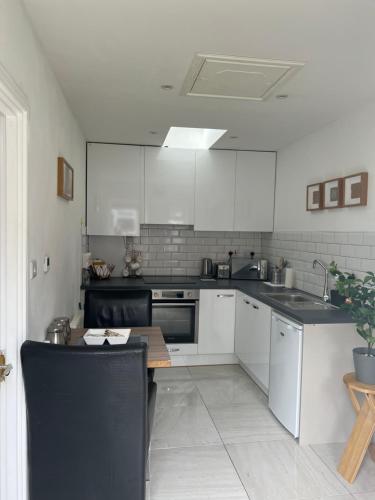 伦敦Dannifar Guest House的厨房配有白色橱柜和桌子