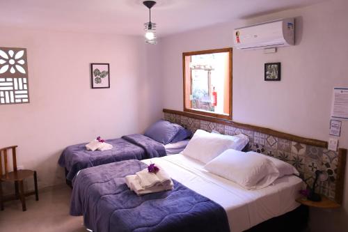 AlexâniaPousada Luz dos Olhos的带紫色床单的客房内的三张床