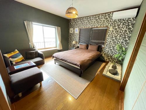 广岛Hiroshima Danbara LiBPLUS的一间卧室配有一张床、一张沙发和一把椅子
