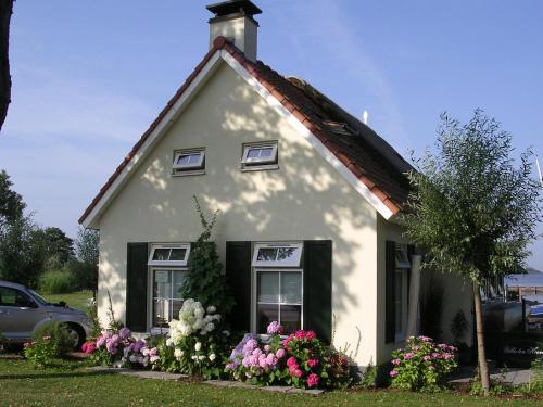SteendamAttractive holiday home with jetty的前面有鲜花的白色房子