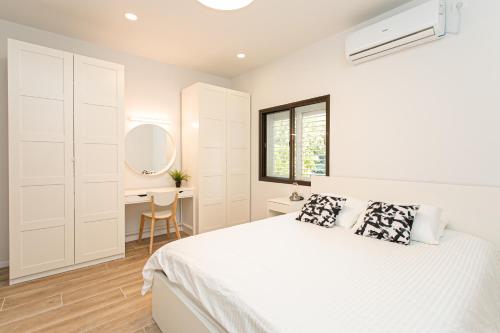 海法Carmel Boutique Apartments的白色卧室配有床和书桌