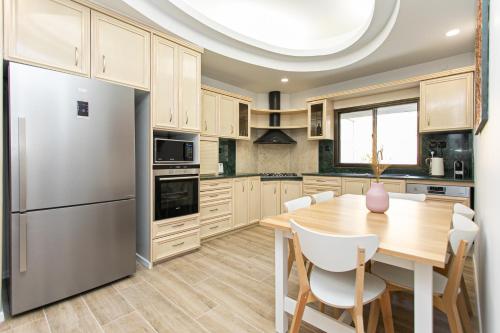 海法Carmel Boutique Apartments的厨房配有木桌和不锈钢冰箱。