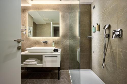 斯普利特Amphora Hotel的浴室配有盥洗盆和带镜子的淋浴