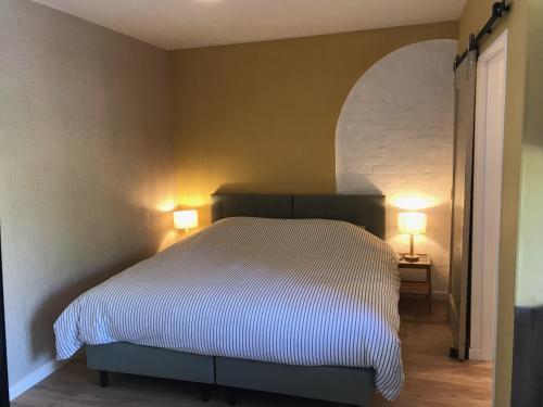 斯容代克t Schooltje的一间卧室配有一张带两盏灯的床。