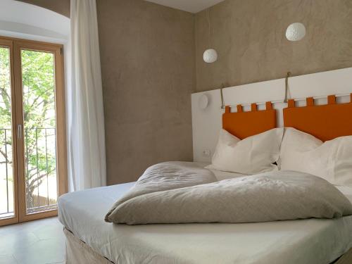 梅拉诺Rennweg 114的一间卧室配有一张带橙色床头板和窗户的床。