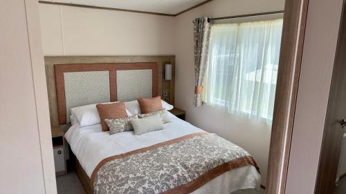 塔特舍尔Luxury Hotub Lodge with Lake View at Tattershall Lakes的卧室配有带枕头的床铺和窗户。
