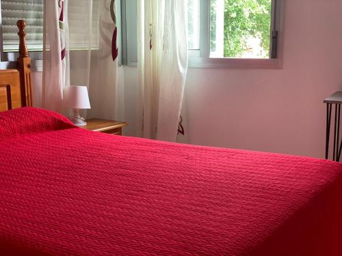 托雷德尔马尔Hostal Mediterraneo的卧室内的一张红色的床,卧室设有窗户