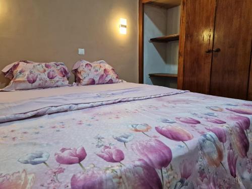 NkongsambaLa Cité des Anges的一张带粉红色床罩的床上花卉床罩