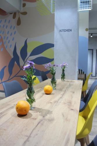 比什凯克izzzi hostel的一张木桌,上面有花瓶和橙子