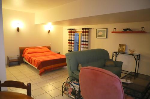 波尔蒂拉盖Mas de Bellegou的一间卧室配有一张床、一张沙发和一把椅子