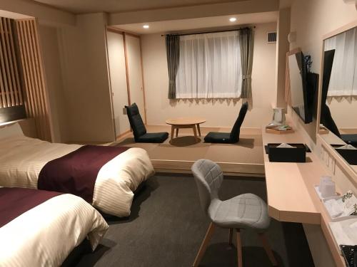 会津若松Aizu Tsuruya Hotel的酒店客房带两张床和一张桌子以及椅子。