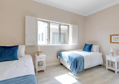赫曼努斯Seafront Retreat in Sandbaai的一间卧室设有两张床和窗户。