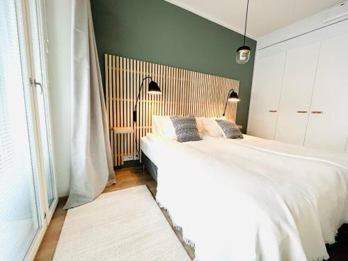 坦佩雷Uusi upea kaksio Tampereen ytimessä, pysäköinti, iso lasitettu parveke的卧室设有一张白色大床和绿色的墙壁