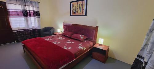 WinnebaLord's Hands Guesthouse Hotel的一间卧室配有一张红色棉被的床