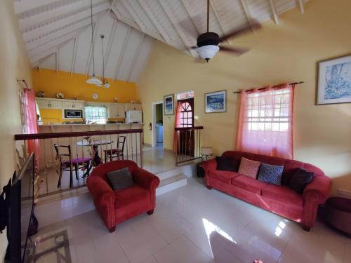 格罗斯岛BenCastle Villa的一间带两张红色沙发的客厅和一间厨房