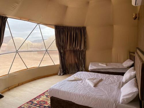瓦迪拉姆Al Rifi Luxury Camp的客房设有两张床和大窗户。