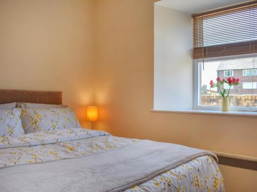 科克茅斯Hatters Croft的一间卧室设有一张床和一个花瓶的窗户