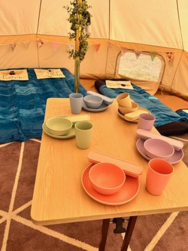 圣贾斯特Sadies Sanctuary的帐篷顶部的桌子,上面有盘子和杯子