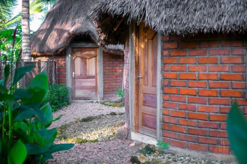 姆特瓦拉AFLII Guest house的茅草屋顶和门的砖砌建筑