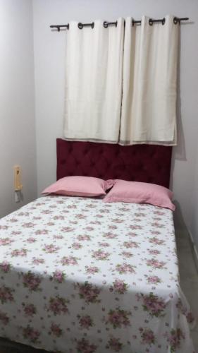 卡鲁阿鲁Casa Confortável的一间卧室配有带粉红色枕头的床和窗户。