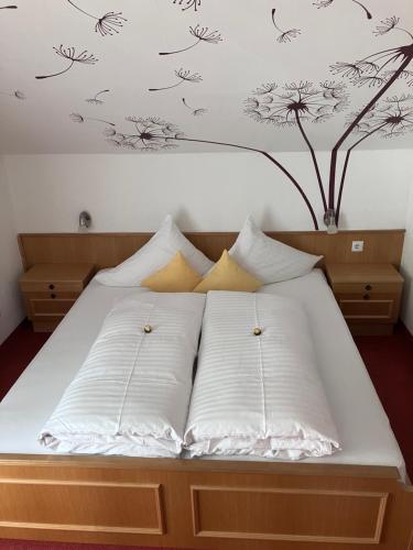 考恩台尔普兰肯斯特纳酒店的一张带白色枕头的床和墙上的树