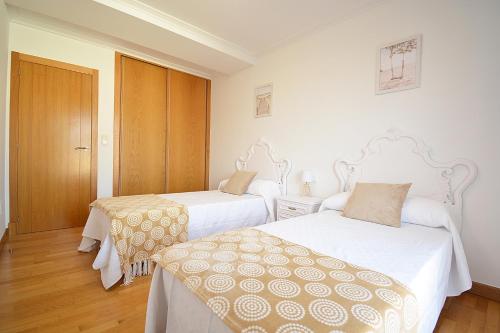 坎巴多斯Céntrico apartamento con parking en Cambados的配有白色墙壁和木地板的客房内的两张床