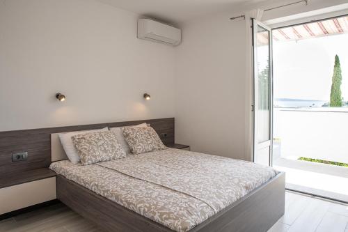 拉布Apartmani Vrtodusic的一间卧室设有一张床和一个大窗户