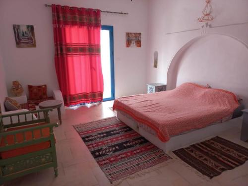 米多恩villa la rose des sables的一间卧室配有床、红色窗帘和地毯